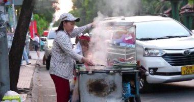 Sokak yemeklerinden anlayan bir kadın sokakta et kızartıyor. Sağlıksız koşullarda satılıyor. Fakirler, ucuz yemekler, ucuz yemekler, motosikletler, arabalar, gerçek hayat. Vietnam Ho Chi Minh Şehri 06.03.2024 