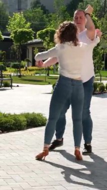 Genç bir çift doğada bachata dansı yapıyor, uzun boylu, güçlü bir adam, kıvırcık saçlı bir kız, yakışıklı Avrupalılar. Bachata dışarıda.