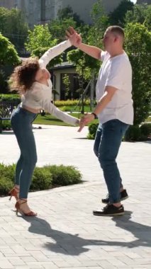 Genç bir çift doğada bachata dansı yapıyor, uzun boylu, güçlü bir adam, kıvırcık saçlı bir kız, yakışıklı Avrupalılar. Bachata dışarıda.