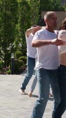 Kharkiv, Ukrayna 'nın merkezinde erkek ve kız güzel bir şekilde dans eder. Kot ve tişörtlü birkaç çift doğada dans eder.