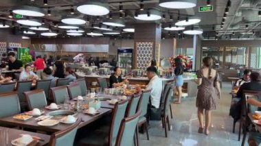 Suşi büfesinden lezzetli yiyeceklerle dolu beyaz bir tabak. Somon nigiri ve maki rulo. Bir el maki dürümlerinden birini yemek çubuğuyla alıyor. Ho Chi Minh Şehri Vietnam 06.06.2024