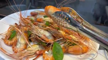 Haşlanmış karides paylaşım tabağı. Kesme tahtasındaki bir kasede haşlanmış karides hazır. Karanlık bir arka planda.