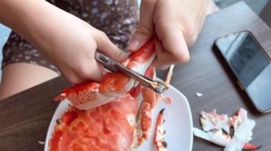 Kız kanseri kaynar sudan çıkarıp diğerleriyle birlikte bir tabağa koyuyor. Restoranda yengeç yiyen bir kız.