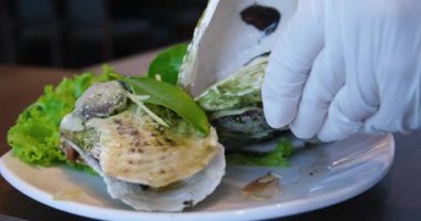 Aşçı, lüks oteldeki lüks bir restorandaki istiridyenin içindeki kaynamış istiridyeleri açar ve çıkarır. Bir istiridye aç.