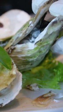 Aşçı, lüks oteldeki lüks bir restorandaki istiridyenin içindeki kaynamış istiridyeleri açar ve çıkarır. Bir istiridye aç.