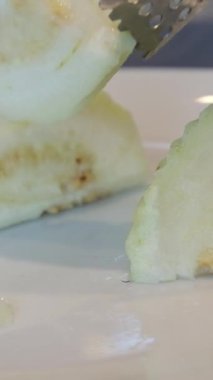 Hint baharatlarıyla servis edilen yakın plan guava salatası. Beyaz tabakta yeşil tuz..
