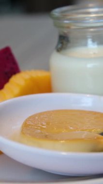 Limon dilimli bir tabakta limon jölesi. Bir kaşıkla vuruyorum ve sallanıyor. Güneş ve mavi gökyüzü. Yakın plan.