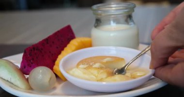 Limon dilimli bir tabakta limon jölesi. Bir kaşıkla vuruyorum ve sallanıyor. Güneş ve mavi gökyüzü. Yakın plan.