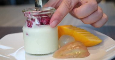 Kavanozda Pitahaya Ejder Meyveli Yunan yoğurdu. Plastik kavanozda yabanmersinli yoğurt karıştıran kişi. Mağaza yabanmersinli yoğurt aldı. Meyveyle yoğurdu karıştır.