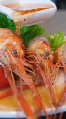 Profesyonel şef akşam yemeği için lezzetli bir tabakta karideslerin üzerine yeşil sos döküyor. Haşlanmış karidesin üzerine balık sosu serpiştir. Karidesin üzerine sos dök.