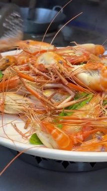 Suşi büfesinden lezzetli yiyeceklerle dolu beyaz bir tabak. Somon nigiri ve maki rulo. Bir el maki dürümlerinden birini yemek çubuğuyla alıyor. Suşi büfesi. Yemek Konsepti. Haşlanmış karides