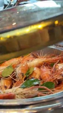 Suşi büfesinden lezzetli yiyeceklerle dolu beyaz bir tabak. Somon nigiri ve maki rulo. Bir el maki dürümlerinden birini yemek çubuğuyla alıyor. Suşi büfesi. Yemek Konsepti. Haşlanmış karides