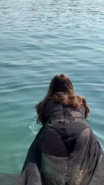 Genç bir kız denizde dinleniyor, siyah bir pareo ile yüzüyor, telefonuna oturuyor, lüks bir plajda dinleniyor. Seyahat sürecinin farklı videolarını ayarla