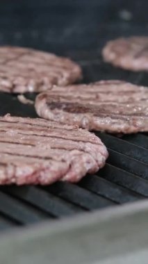 Izgarada Amerikan yağlı hamburgeri pişiriyorum. Hamburgercinin biftek ya da domuz pirzolası ezmesi. Restoranın mutfağında hamburgerler için pirzola yapan şef biftek ezer. Hızlı ve
