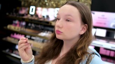  Genç bir kız Kanada 'da Vancouver' da büyük bir alışveriş merkezinde kozmetik ürünleri seçiyor. Bir mağazada yürüyen merdivene binmek.