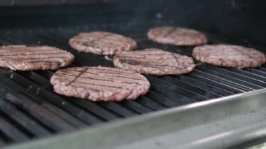 Izgarada Amerikan yağlı hamburgeri pişiriyorum. Hamburgercinin biftek ya da domuz pirzolası ezmesi. Restoranın mutfağında hamburgerler için pirzola yapan şef biftek ezer. Hızlı ve