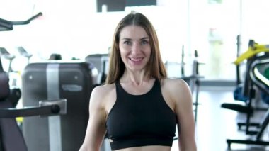 Spor salonunda kollarını sallayan bir kadın. Bench Press Spor Salonu 'nda dambılla spor yapan bayan sporcu. Sağlıklı ve zayıf vücut için ağırlık kaldırarak göğüs kaslarını çalıştıran genç bir kadın..