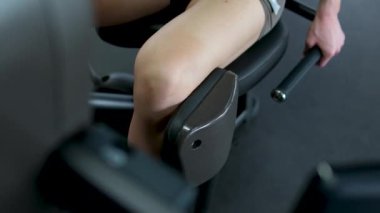 Spor salonunda bacak egzersizi yapan bir kadının yakın çekimi. Bir erkek ve bir kadın spor salonunda antrenman yapıyor. Beden eğitiminde bacak kaslarını şişir.
