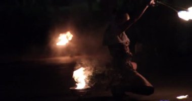 Dişi ateş dansçısı yanan sopa çeviriyor hareket halinde parlak izler yaratıyor açık havada karanlık izler bırakıyor, kıvrılıyor. İtfaiye kadını Vietnam Ho Chi Minh Şehri 06.17.2024