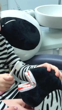 Çocuk kız sabahları aynanın önünde dişlerini fırçalıyor. Sağlık hizmeti konsepti. Bir kız küçük bir zebra oyuncağının dişlerini fırçalıyor.