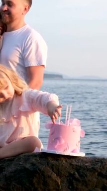 Ebeveynler küçük kızlarına hayrandır, çocuk bir pastayla oturur, bir doğum günü partisi verir, açık havada okyanus kıyısında kutlar. Samimi sevgi ve şefkat.