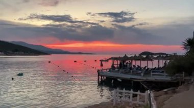 Gün batımında kumlu bir sahilde sakin dalgalar. Arnavutluk plajı