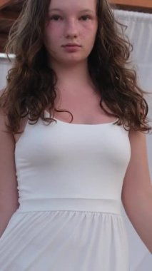 Mutlu bir kadın kumsalda nehir kıyısında yürüyor ve suya giriyor. Arkadan bakan kız doğanın tadını çıkarıyor. Yeşil ağaçsız. Sihirli güneş ışığı gökyüzü. Bayan ipek beyaz elbiseyle yürüyor. Rüzgarda ağır çekimde uçuyor..