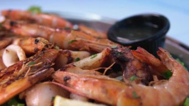 Tatlı ve ekşi soslu kızarmış karideslerin kamera hareketi sarımsaklı baharatlar ve limon ve ahududu ile servis edilen baharatlar. Pişmiş karideslere yaklaş. Deniz ürünleri. Makro gıda arka planı.