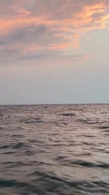 Hava görüntüsü. Alacakaranlıkta okyanusun üzerinde uçmak, pembe bulutlarla suyun üzerinde uçan hava manzarası. Okyanusun üzerinde pembe gökyüzü.