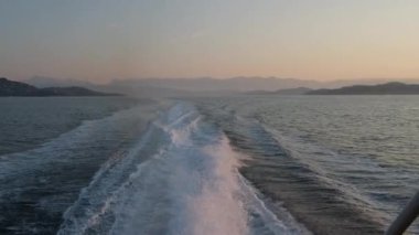 Güneş batarken beyaz dalga köpüğü ve gemi kabarcıkları denizde ya da okyanusta hareket eder. Gün batımında tekne üstüne tekne. Deniz suyu.