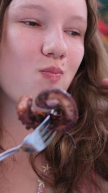 Ahtapot yiyen kız. Avrupalı kadınların iştahı. Lezzetli karides ahtapot deniz ürünleri. Terasta bir yaz restoranı. Kapalı yüz beyaz ten. zevk