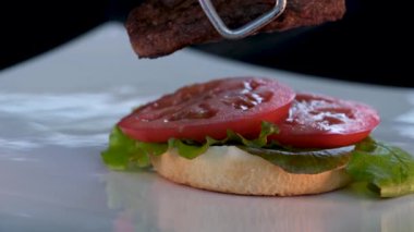 Lezzetli bir burger. Yakın plan. Pirzola, soğan, marul, altın sarısı gevrek somun. 