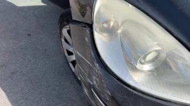 Araba farı kırılmış, kaputu çökmüş ve trafik kazasından sonra tamponu hasar görmüş. Arabanın farları kırık.