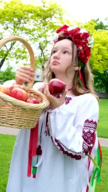 Ormanda elinde bir sepet elmayla geleneksel Rus kıyafetleri içinde genç bir kadın. Ukraynalı kız elmaları