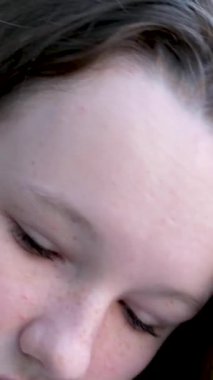 Genç, hoş bir kadın, beyaz kazaklı bir terzi, mavi bir ev bitkisi duvarının arka planında, masada makasla hafif bir kumaş kesiyor. Yüksek kalite