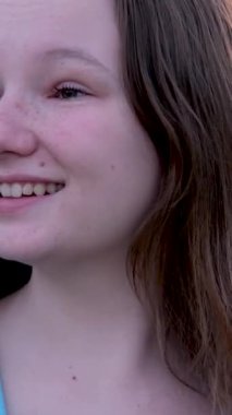 Genç bir kız sıcak ve güneşli bir akşamda ellerini sallıyor. Mavi ceketli, Avrupalı. Uzun saçlı, gülümseyen