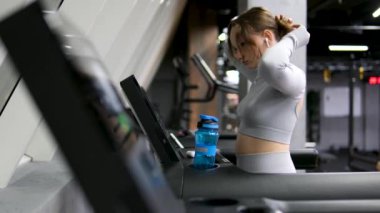 Açık havada elinde su şişesiyle koşan zinde bir kadın. Spor salonundaki kadın antrenmandan sonra ara verdi. Spor salonundaki kız su içiyor.