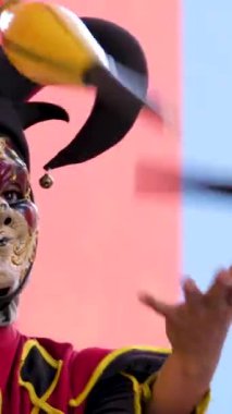 Kırmızı burunlu palyaço parkta renkli toplarla hokkabazlık yapıyor. Steampunk 'ın bıyıklı pis palyaçosunu parkta sirk numaraları yaparken çekmiş. Grand World, phu Quoc Adası, Vietnam Soytarısı