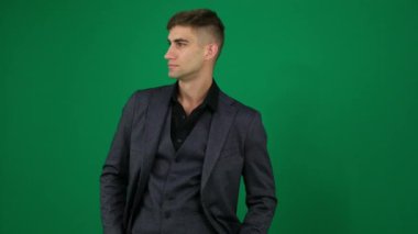 Eller cepte, adamım. Siyah smokinli şık moda adamının el ele tutuşup smokini ayarlarken ve koyu gri arka planda ışık yanıyorken görüntüsü.