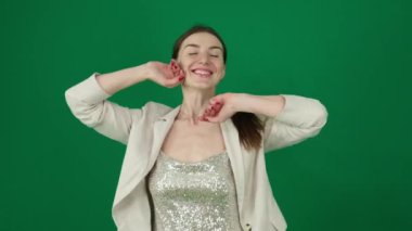 Genç bir kadın yeşil arka planda dans ediyor. Kromakey bir kadın, güzel, gümüş bir elbise giyiyor. Ceket gülümsüyor. Sevgili kızım.