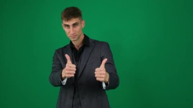 Yeşil arka plandaki yakışıklı adamın duyguları... Kromakey yakın plan koyu renk saçlı genç adam... iş ilanı. Parmak 'ın iki elini de uzaya kaldırmasını onaylayın. bir ürün öneriyor