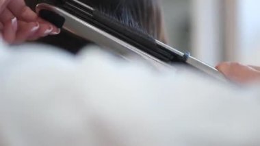 Kuaför, kuaför saç maşası kullanarak kuaförde tanınmayan bir kadının uzun saçlarını yaptırıyor. Güzellik ve moda kavramı. Kuaför kuaför saç stili yapar.