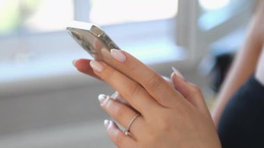 Genç kadınlar akıllı telefon tutarlar. Kadın eli telefonu tutuyor. Kadınların parmakları hassas dokunmatik ekranlara rehberlik ediyor. Uygulamadaki videolar düzenleniyor. İçerik oluşturmak için teknoloji aygıtı kullanılıyor