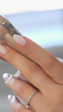 Genç kadınlar akıllı telefon tutarlar. Kadın eli telefonu tutuyor. Kadınların parmakları hassas dokunmatik ekranlara rehberlik ediyor. Uygulamadaki videolar düzenleniyor. İçerik oluşturmak için teknoloji aygıtı kullanılıyor