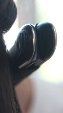 Düz ütüyle saçını kıvıran bir kadının yakın çekimi. Kuafördeki güzel kız. Güzellik salonu. Kıvırcık Saç