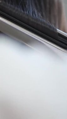 Kuaför, kuaför saç maşası kullanarak kuaförde tanınmayan bir kadının uzun saçlarını yaptırıyor. Güzellik ve moda kavramı. Kuaför kuaför saç stili yapar.