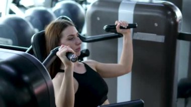 Sportif kadınlar kol kaslarını şişirmek için egzersiz aletleri kullanır. Formda sporcu, işten sonra modern spor salonunda yoğun egzersizden hoşlanır. Beden eğitiminde kollarını aç.