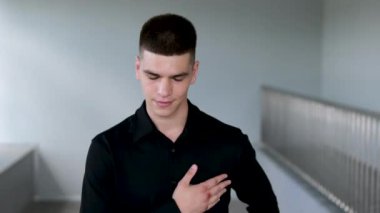 Elini kalbine koy, başını eğ, kalp ağrısı minnettarlığını göster. Siyah saçlı ve mavi gözlü yakışıklı bir adam. Melez ırk uyruğu
