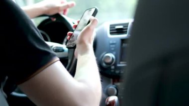 Adam arabada oturuyor ve telefon ekranına bakıyor. El ele tutuşan telefon direksiyonu. Siyah saçlı ve mavi gözlü yakışıklı bir adam. Melez ırk uyruğu