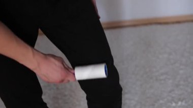 Tişörtten tüy ve yünü pamuklu bir rulo ile çıkarıyor. Kıllı silindir tutan adam..